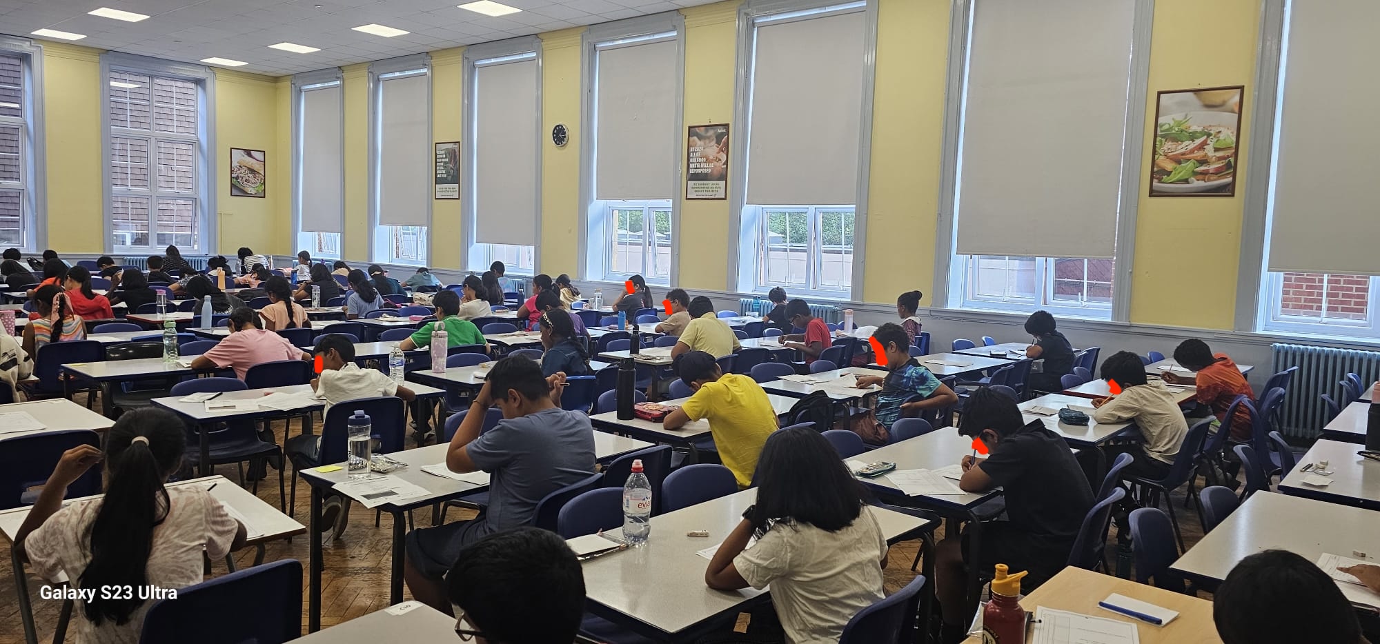 Panoramic view of a full GLECTA mock test room from the back, children working at desks